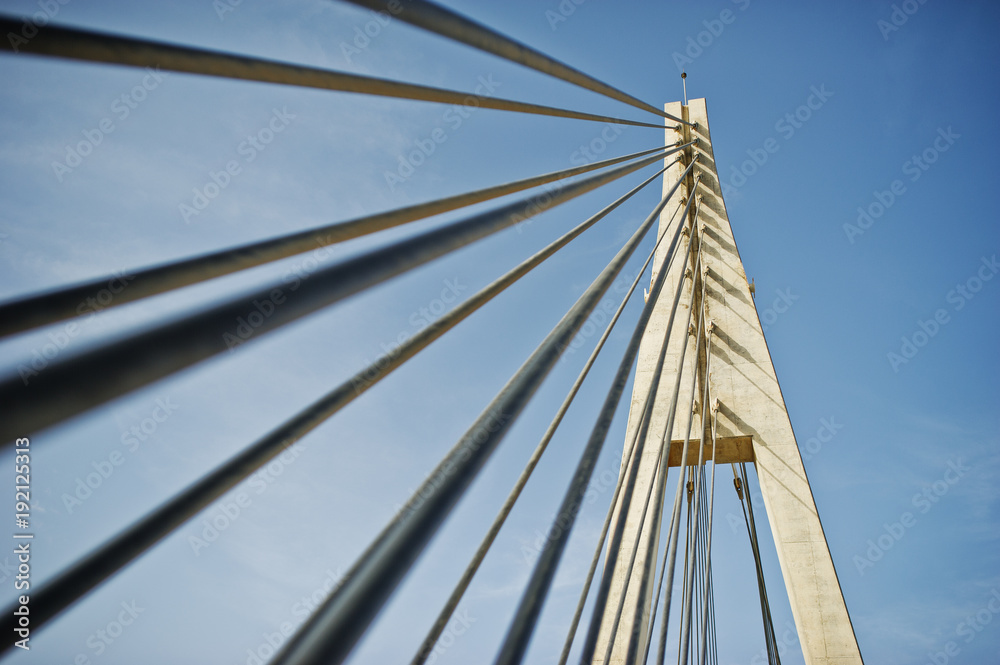 Tall white bridge in a city. Close-up photo of its ropes. Tall white bridge in a city. Close-up photo of its ropes.