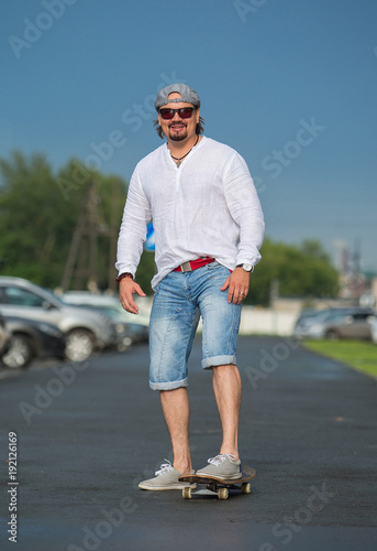 A man is riding a skateboard outside on a sunny day. Sport, movement, pleasure.
