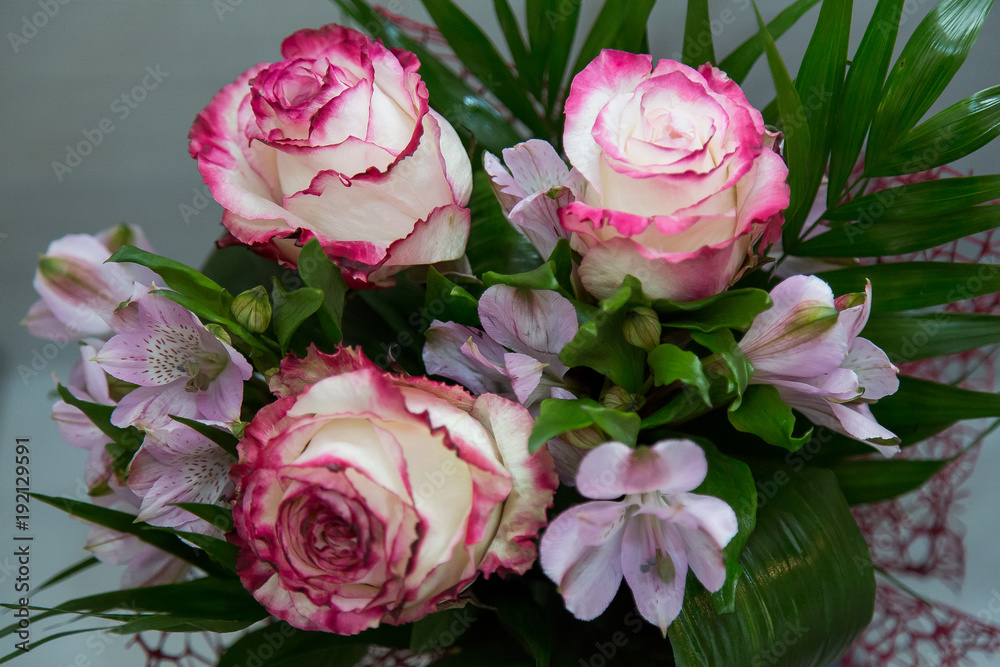 Fototapeta premium A wonderful bouquet of white roses with red flowers and spring flowers