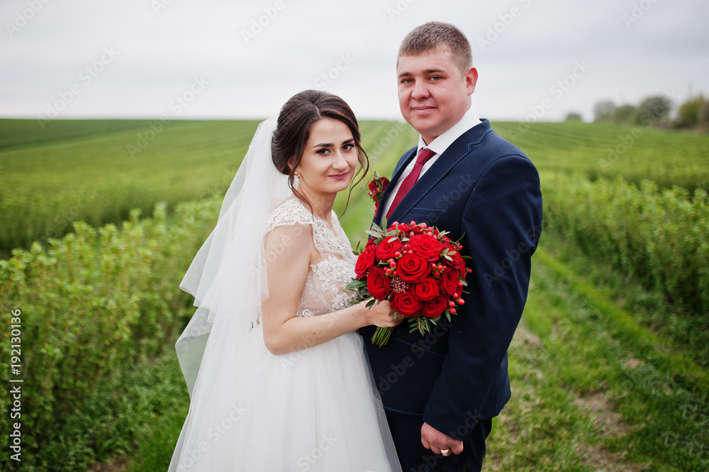 Attractive young wedding couple posing on the blackcurrant field on their wedding day. Attractive young wedding couple posing on the blackcurrant field on their wedding day.