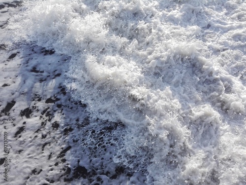White foam of sea water waves as texture or background. Aerial view of water surface background, white foam of sea waves texture. Watersplashes as sea waves and foam background. Close-up of sea foam.