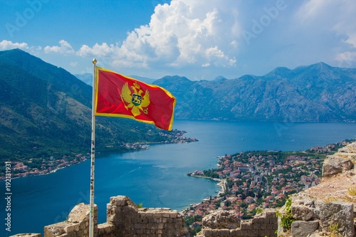 Beautiful view from above on the Kotor and Bay of Kotor, Montenegro. Waving in the wind flag of Montenegro on Ancient fortress wall above Kotor.