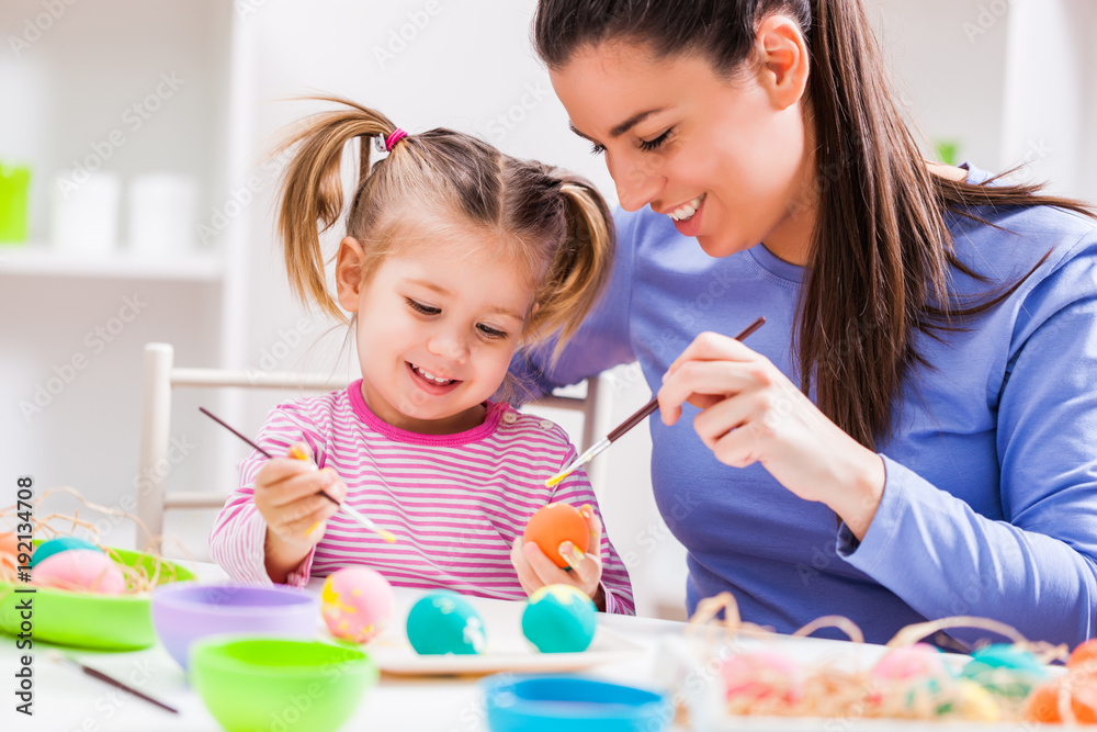 Fototapeta premium Happy mother and daughter coloring eggs for Easter.