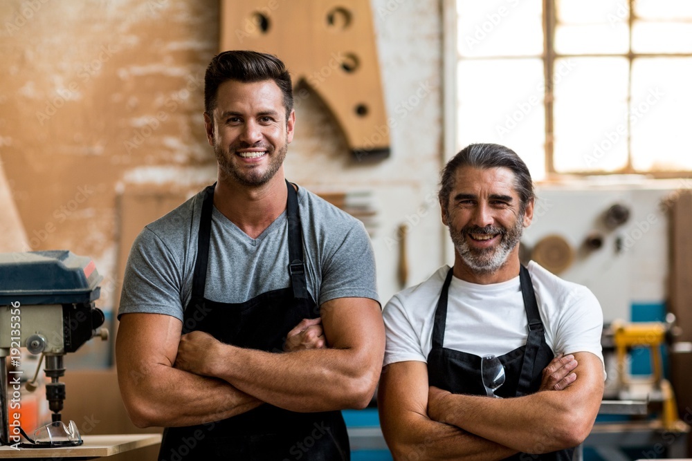 Carpenters standing with arms crossed in workshop Carpenters standing with arms crossed in workshop