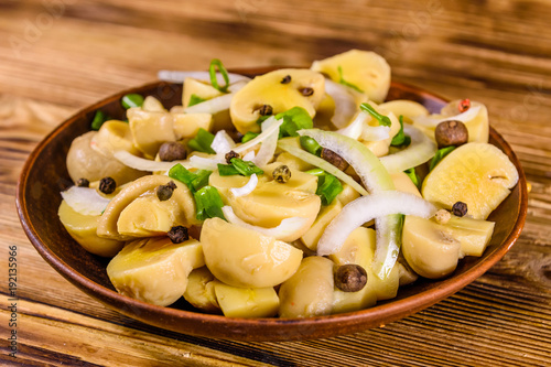 Ceramic plate with canned mushrooms on wooden table