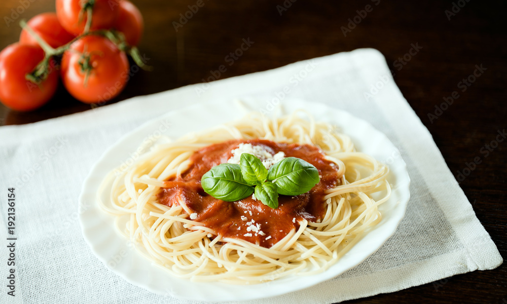Italian pasta spaghetti topped with a tomato and fresh basil Italian pasta spaghetti topped with a tomato and fresh basil