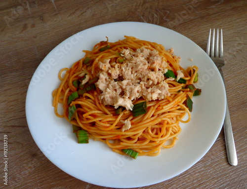Spaghetti with tuna fishand vegetable sauce in the plate, wooden table, top view