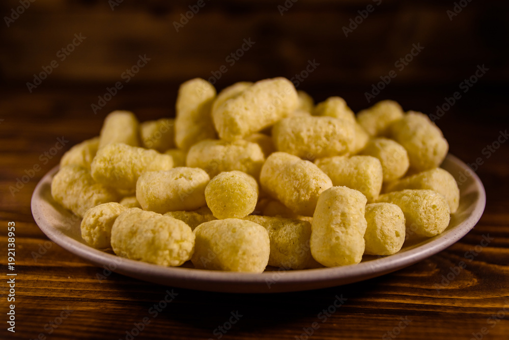 Ceramic plate with corn sticks on wooden table Ceramic plate with corn sticks on wooden table