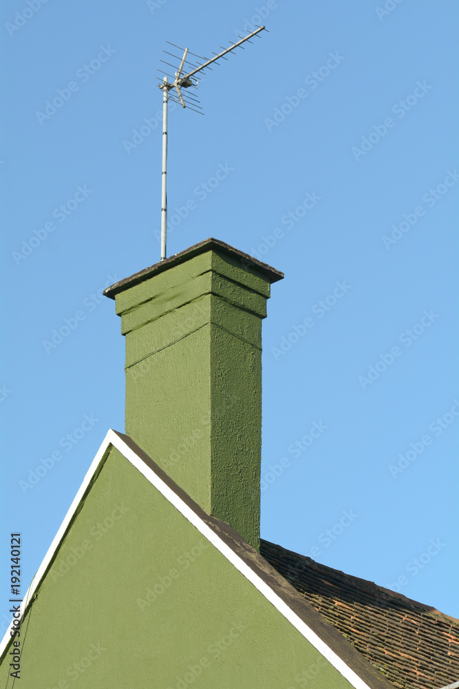 Chimney stack and tv aerial on roof of house - the render on this property has been painted a deep green colour