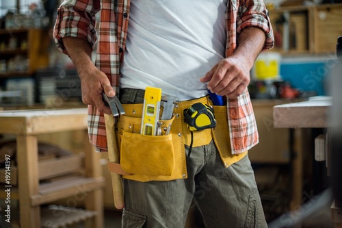 Carpenter removing hammer from tool belt photo
