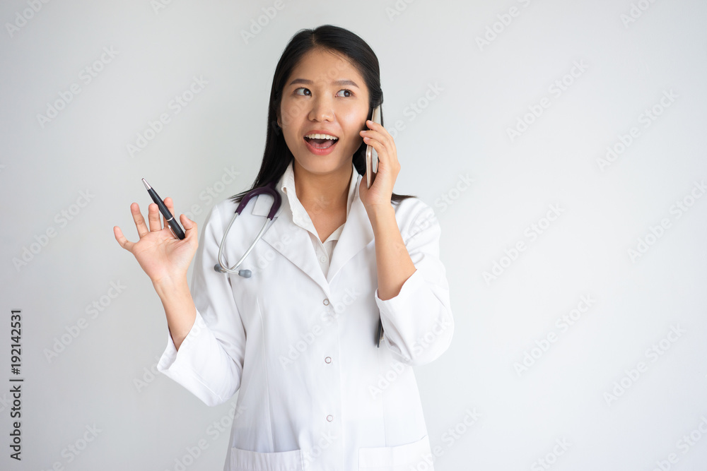 Surprised excited Asian doctor talking on phone Surprised excited Asian doctor talking on phone