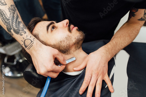 Close up image of barber makes beard cut of a man photo