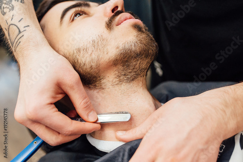 Close up image of barber makes beard cut of a man photo