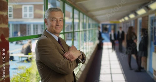 Wallpaper Mural 4K Portrait friendly relaxed teacher in school with students chatting in background. Slow motion Torontodigital.ca