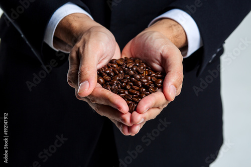 Businessman's hands holding fresh roasted coffee beans isolated on white background