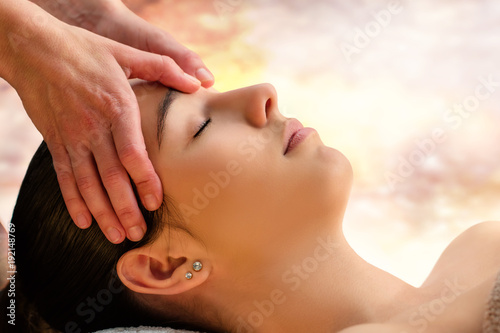 Massage therapist touching sensitive area between eyes on woman.