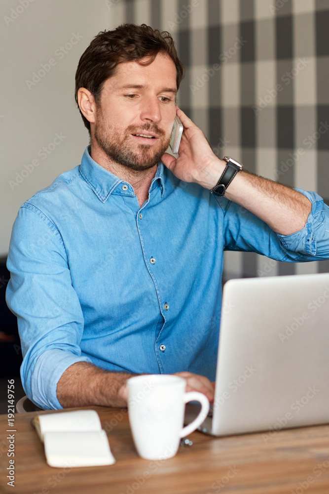 Handsome man talking on a cellphone and working online Handsome man talking on a cellphone and working online