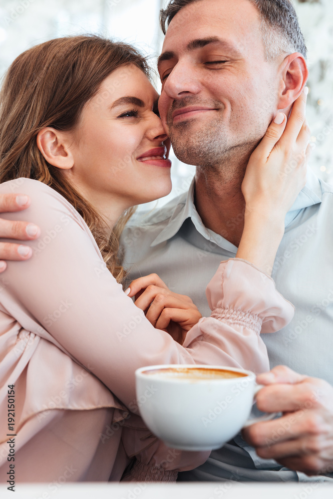 Joyful married couple hugging and having fun together in cozy city cafe, with public display of affection Joyful married couple hugging and having fun together in cozy city cafe, with public display of affection