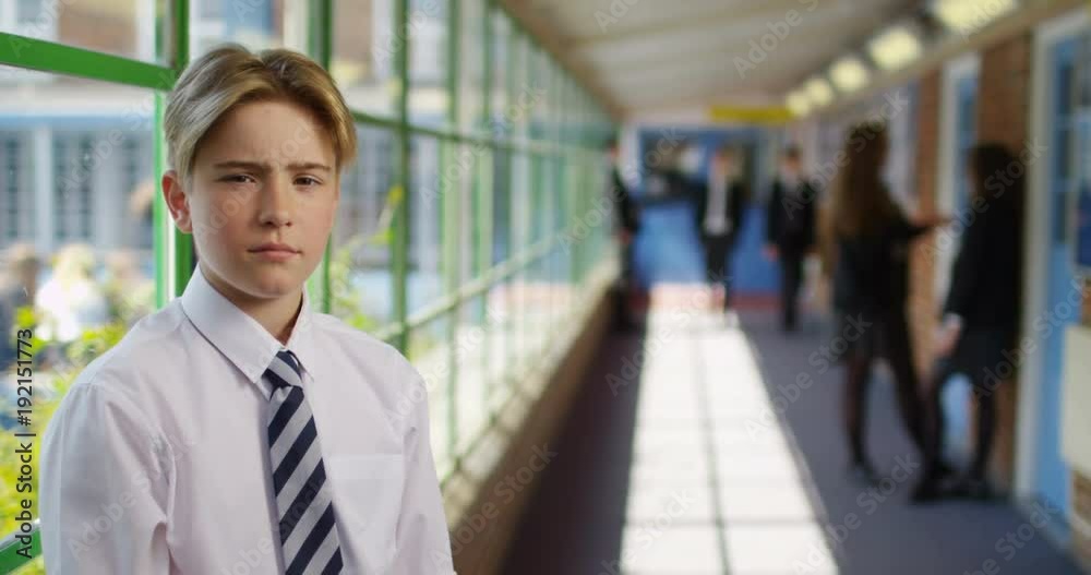 4K Portrait serious school boy breaking into a smile, standing in school hallway. Slow motion 4K Portrait serious school boy breaking into a smile, standing in school hallway. Slow motion