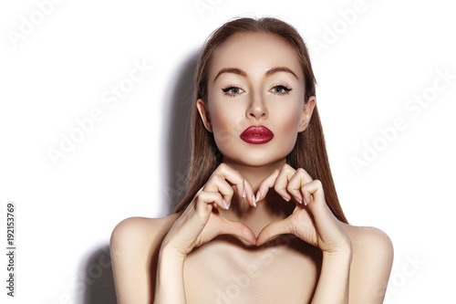 Romantic young Woman making Heart Shape with her Fingers. Love and Valentines Day Symbol. Fashion girl with Happy Smile photo