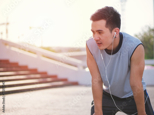 Handsome asian young man listening to music on earbuds and running in park, Healthy lifestyle concept.
