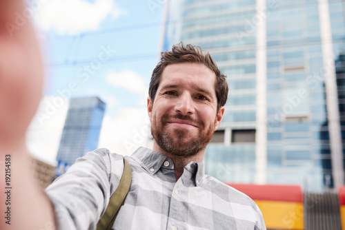 Smiling young man taking a selfie in the city