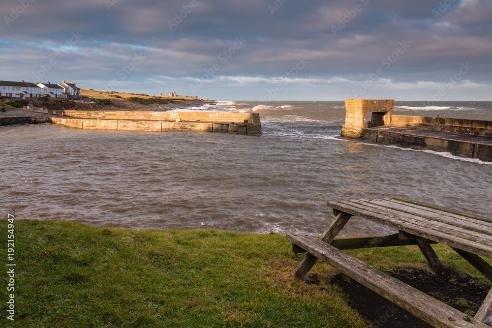 Craster Harbour at High Tide / Craster is a small fishing village on the Northumberland coast, with a small harbour and views to the ruins of Dunstanburgh Castle Craster Harbour at High Tide / Craster is a small fishing village on the Northumberland coast, with a small harbour and views to the ruins of Dunstanburgh Castle