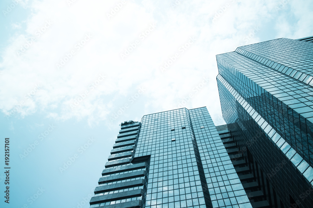 glass reflective office buildings against blue sky with clouds and sun light.