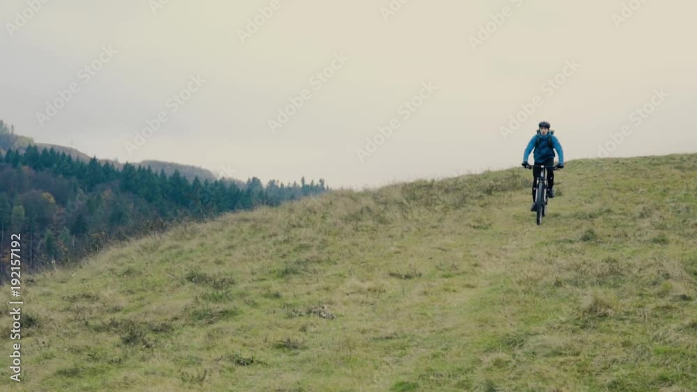Young man riding bicycle down the hill in autumn nature. Young man riding bicycle down the hill in autumn nature.