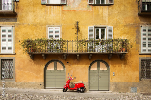 Old red scooter in front of a beautiful building