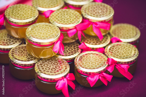 Beautiful cans with honey decorated with pink bows.