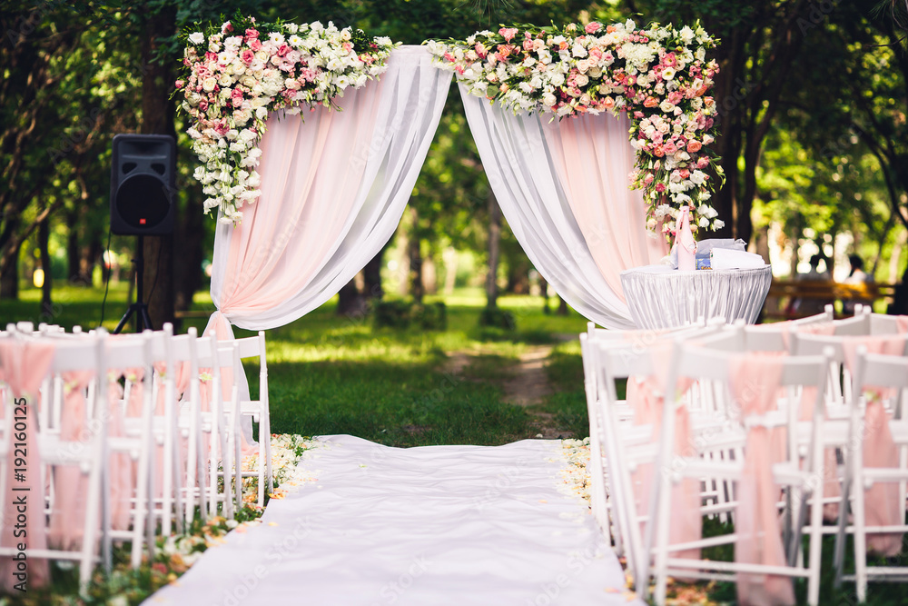 Decor wedding ceremony in the summer in the park: an arch, chairs, flowers, path. - obrazy, fototapety, plakaty 
