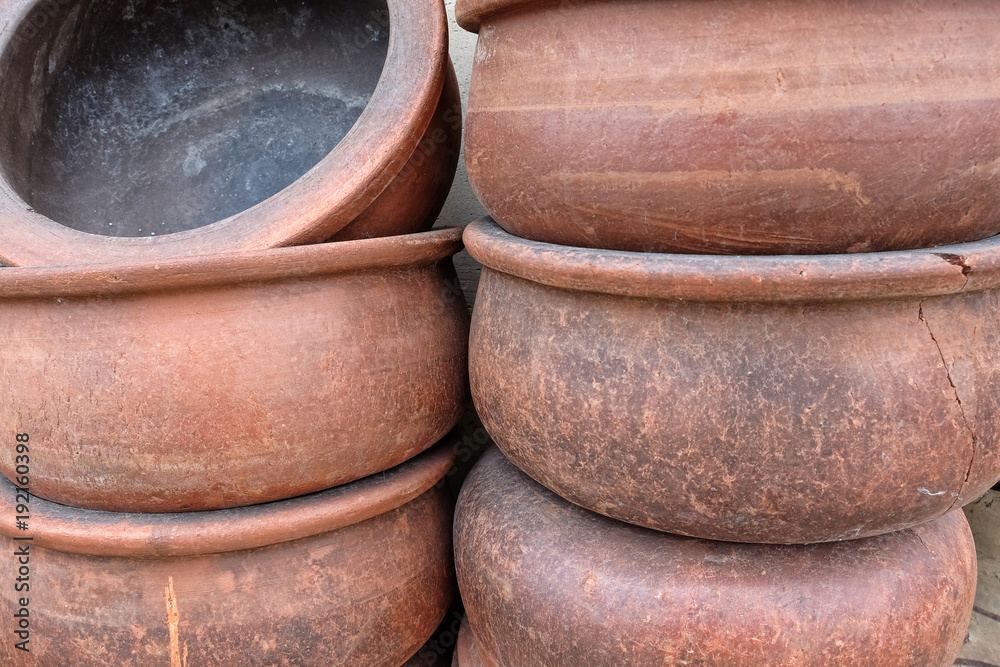 Handmade big clay casseroles stacked in front of the wall Handmade big clay casseroles stacked in front of the wall