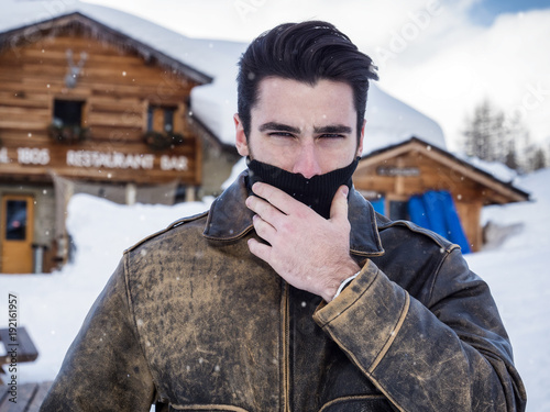 Portrait of adult handsome man covering face with scarf looking provocatively at camera. photo