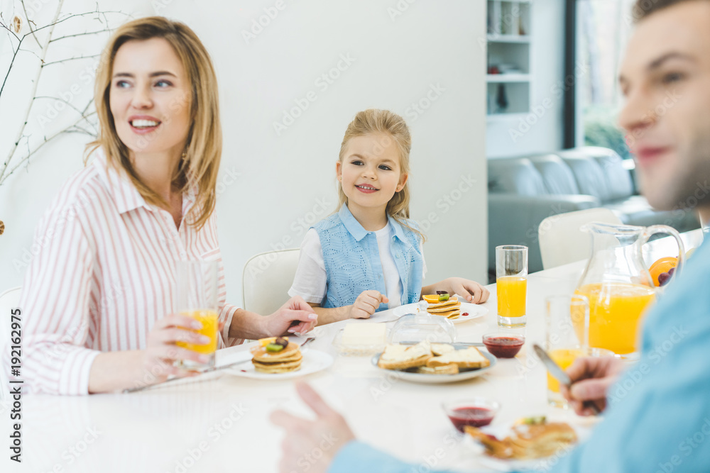 happy family looking away while having breakfast together at home