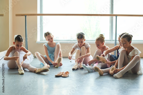 Group of young ballerinas preparing for performance. Six young ballet girls in ballet studio.