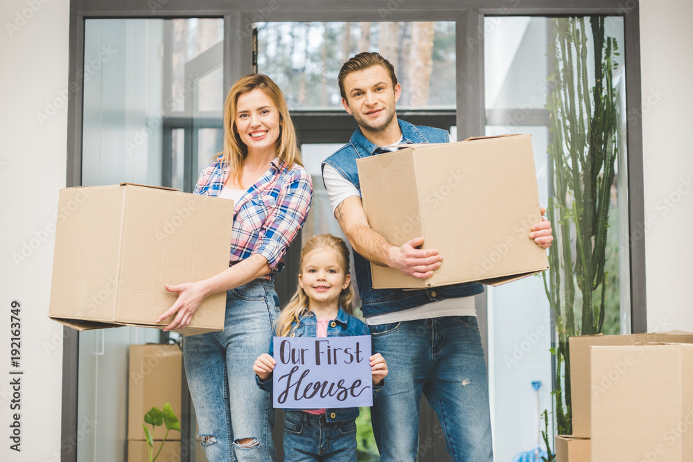 portrait of smiling parents and daughter with our new house board in hands, moving home concept portrait of smiling parents and daughter with our new house board in hands, moving home concept