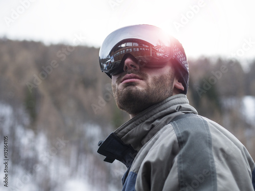 Young handsome man in winter sportswear looking away, wearing big mirrored ski mask © starsstudio