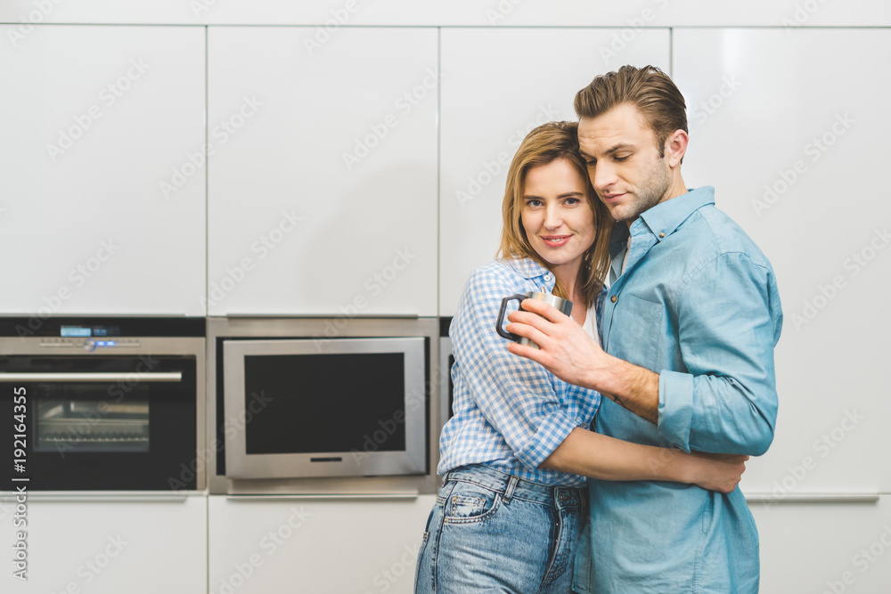 portrait of couple hugging each other in kitchen at home portrait of couple hugging each other in kitchen at home