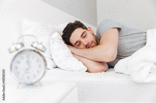 Canvas-taulu Photo of handsome man having stubble and wearing casual clothes, sleeping at hom