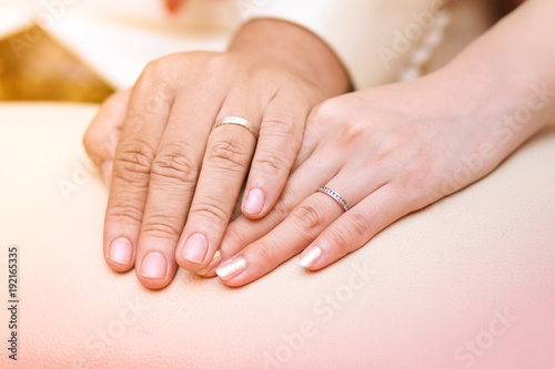Closeup image of man and woman hands with wedding ring holding tenderly.