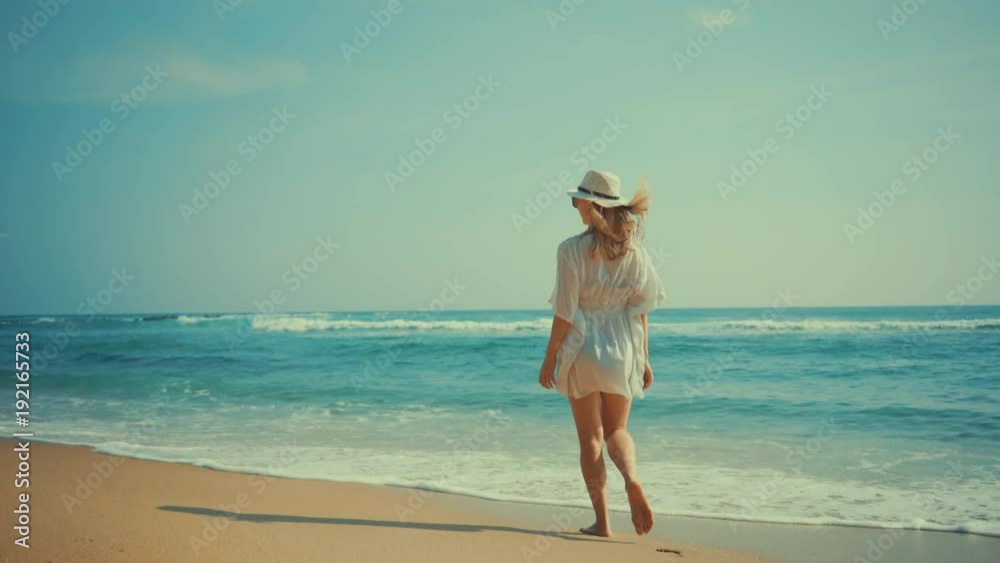 Woman walking on the ocean beach under blue sky in sunny day. Seascape view with palms. Woman walking on the ocean beach under blue sky in sunny day. Seascape view with palms.