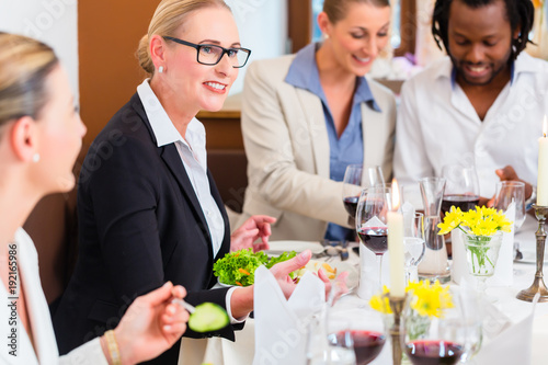 Group of men and women at business lunch in restaurant eating and drinking