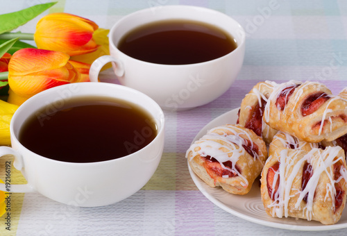 Strawberry pastries on a plate with coffee and flowers
