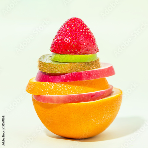 stack of different fruit slices on sofe green background  concept for health care  fruit punch