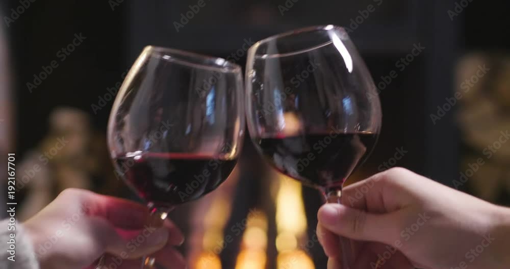 One winter evening a couple sitting in front of the fireplace relaxing, drinking a glass of champagne and making toast to celebrate while enjoying the warmth of the fireplace. One winter evening a couple sitting in front of the fireplace relaxing, drinking a glass of champagne and making toast to celebrate while enjoying the warmth of the fireplace.