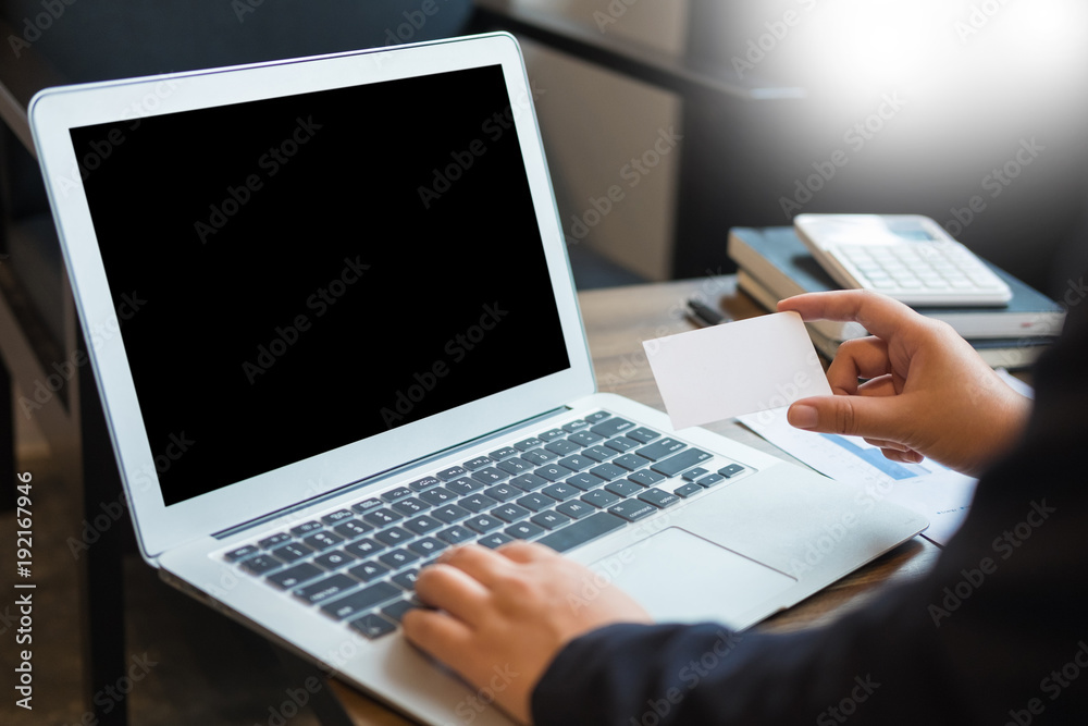 Man holding credit card in hand and entering security code using smart phone on laptop keyboard, online shopping concept Man holding credit card in hand and entering security code using smart phone on laptop keyboard, online shopping concept