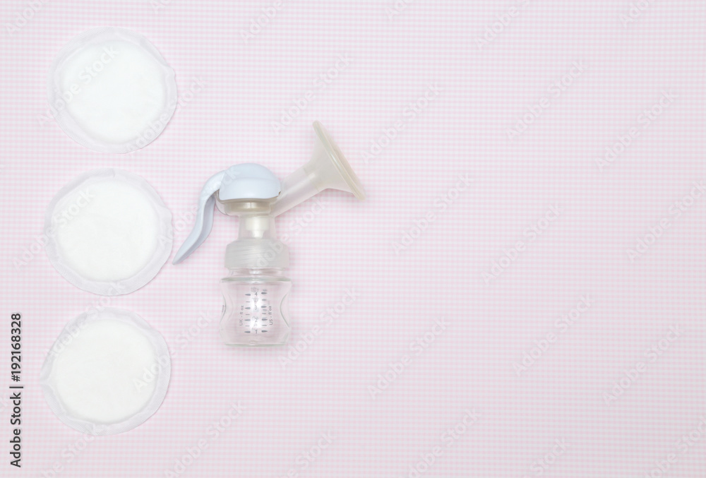 Manual breast pump with breast pads on the pink background