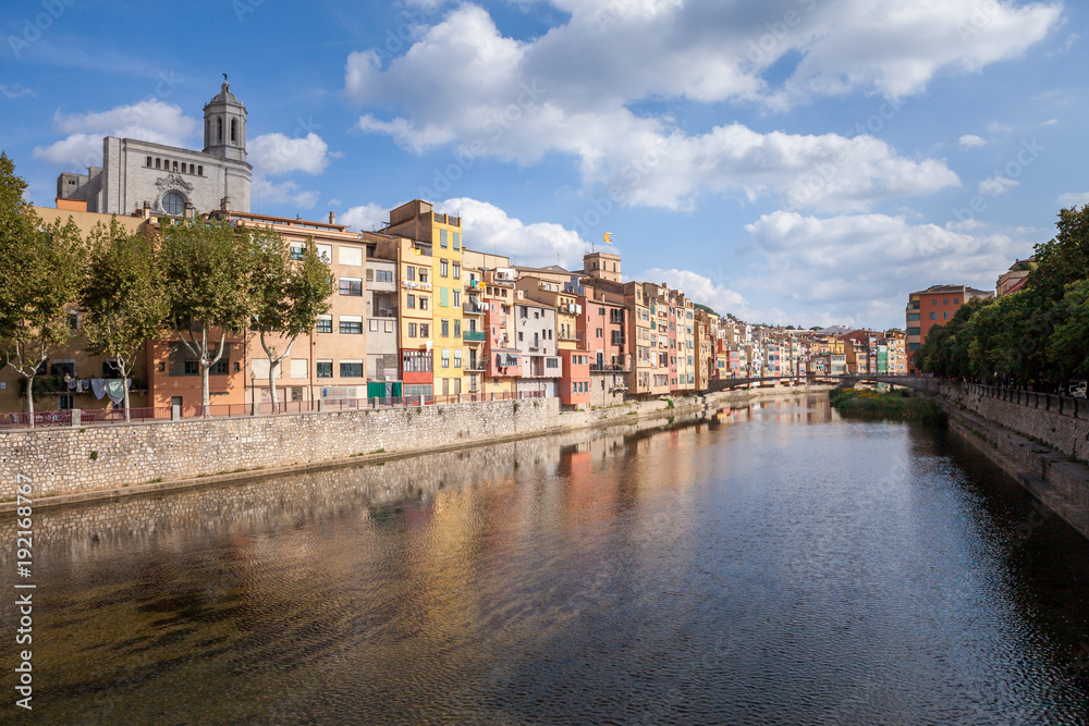 Obraz premium Colorful yellow and orange houses and bridge Pont de Sant Agusti reflected in water river Onyar, in Girona, Catalonia, Spain