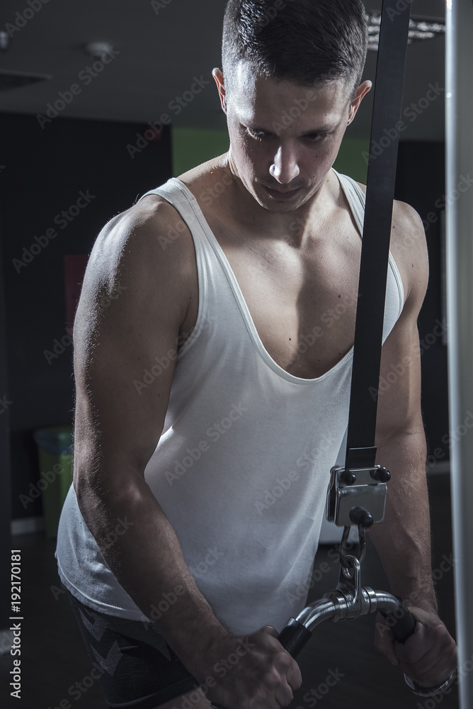 Obraz premium Young caucasian athletic man in the gym doing cable fly exercises